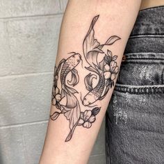 a woman's arm with a fish and flowers tattoo on the left inner arm