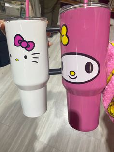 two hello kitty tumblers sitting next to each other