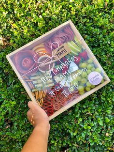 a person holding up a clear box filled with different types of fruits and veggies