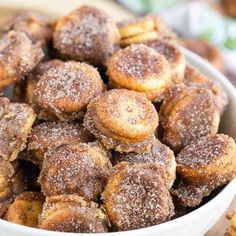 a bowl filled with sugared donuts on top of a table