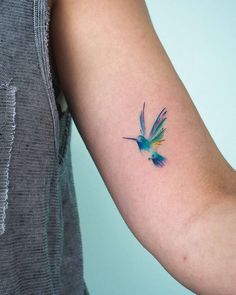 a small tattoo on the arm of a woman's arm with a hummingbird