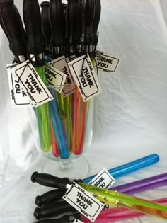 a vase filled with lots of different colored straws next to some black and white tags