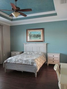 a bedroom with a bed, dresser and ceiling fan in the middle of the room