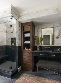 a bathroom with marble walls and flooring has a black vanity, gold accents, and a walk - in shower