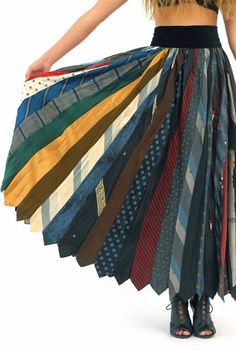 a woman in a black top is holding many different colored ties on her hands and the bottom half of her skirt