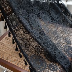 black lacy fabric with tassels on top of a wooden table in front of a window