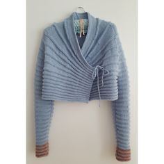 a blue cardigan sweater hanging on a white wall