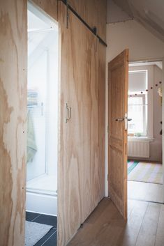 an open door leading into a bedroom with wood paneling on the walls and floor