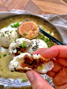 a person is holding some kind of food on a plate with chopsticks in their hand