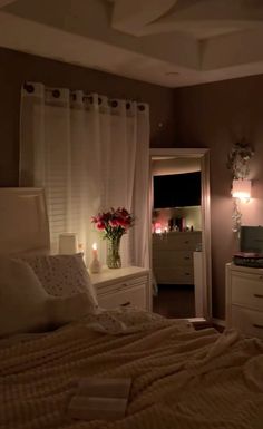 a bed room with a neatly made bed and flowers on the dresser next to it