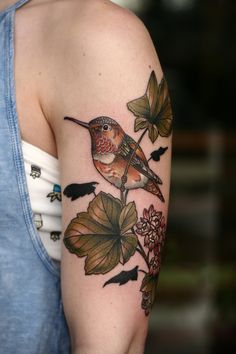 a bird sitting on top of a tree branch with leaves and flowers around its neck