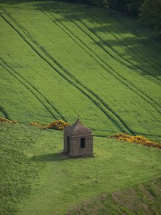 a small building in the middle of a green field with lines drawn on it's sides