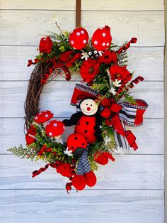 a red and white wreath with a ladybug doll hanging on the front door