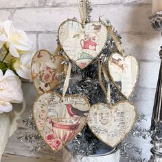 four heart shaped ornaments sitting on top of a tinsel covered pot filled with flowers