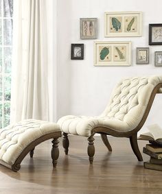 a white chair and ottoman in a room with pictures on the wall behind it,