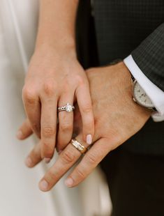 a close up of two people holding hands with wedding rings on their fingers and the other hand