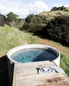 a hot tub sitting on top of a wooden platform next to a lush green field