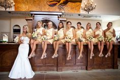 a group of women sitting on top of a counter in front of a bar holding bouquets