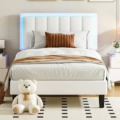 a teddy bear sitting in front of a bed with white headboard and foot board