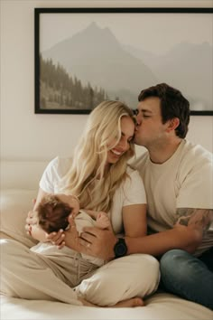 a man and woman sitting on top of a bed with a baby in their lap