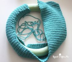 a crocheted blue bag with a green handle and string attached to the inside