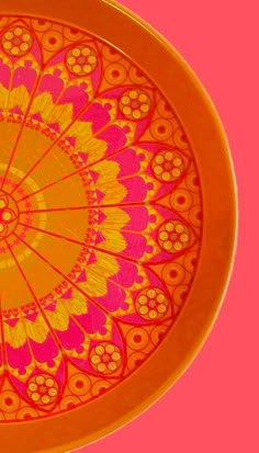 an orange and pink plate with designs on the inside is sitting on a pink surface