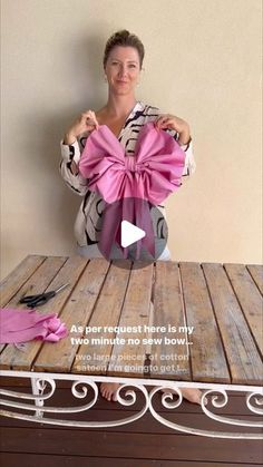 a woman sitting on top of a wooden table holding a pink bow