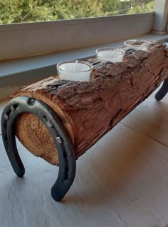 a bench made out of a log with tea cups on it sitting in front of a window