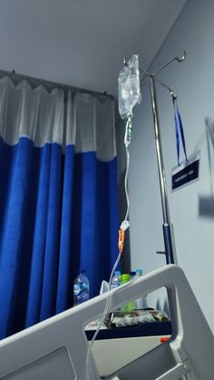 a hospital room with blue curtains and an iv drip attached to the armrests