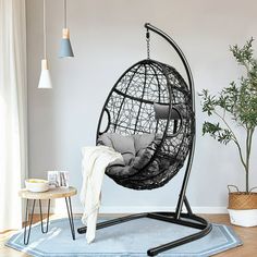 a hanging chair in the corner of a room with a rug and potted plant