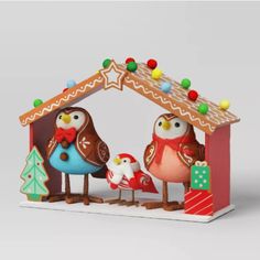 two owls are standing in front of a christmas house with a gingerbread manger