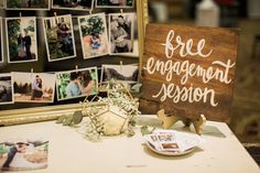 a wooden sign sitting on top of a white table next to pictures and photos hanging on the wall