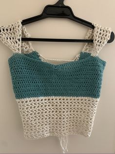 a crocheted top hanging on a hanger