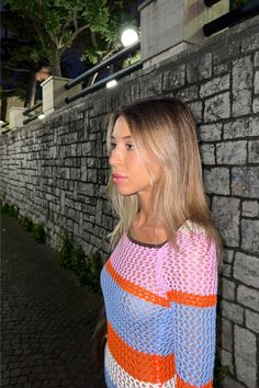 a woman is standing in front of a brick wall and looking off into the distance