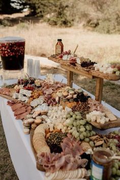 an assortment of cheeses, meats and other food items on a table outdoors