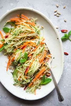 a white plate topped with shredded carrots and veggies