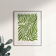 a green and white print hanging on the wall next to a potted cactus plant