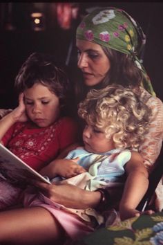 a woman sitting next to two children reading a book