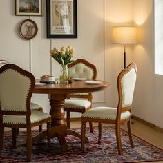 a dining room table with four chairs and a vase filled with flowers on top of it