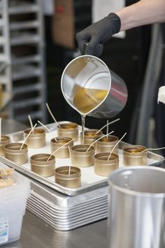 a person pours liquid into small cups on top of a metal tray filled with cookies