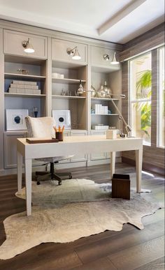 a home office with white furniture and open shelving units on the wall, along with a cow hide rug