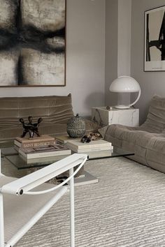 a living room filled with furniture and a large painting on the wall above it's glass top coffee table