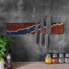 three knives are hanging on the wall next to jars