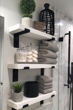 bathroom shelves with towels, soaps and plants on them in black and white colors