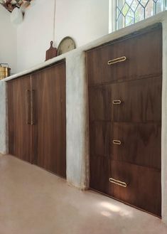 three wooden doors in an empty room with a clock on the wall