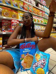 a woman sitting on the floor with cereal in front of her and holding two bags