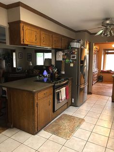 a kitchen with tile flooring and wooden cabinetry in the center, along with an island