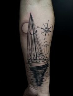 a man's arm with a sailboat and compass tattoo on it