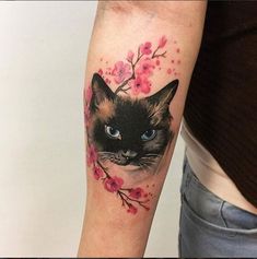 a woman's arm with a cat and cherry blossoms tattoo on her left arm