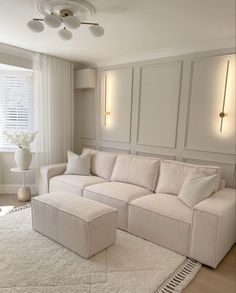 a living room with a large white sectional couch and pillows on the rug in front of it